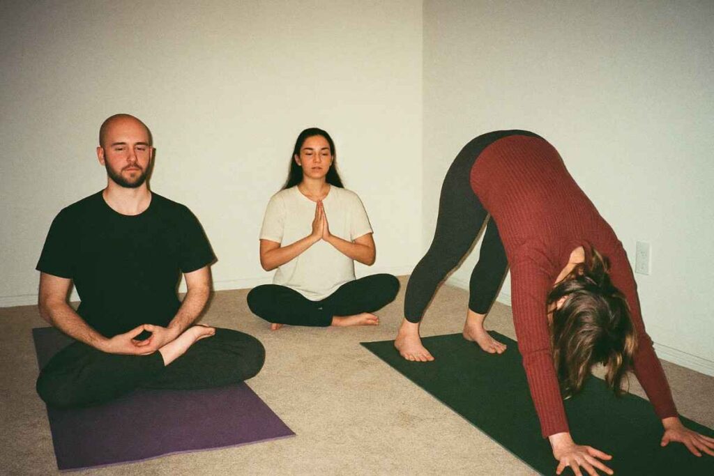 Indoor shot with flash from compact 90s camera, 3 people practicing different yoga poses in a quiet room, each representing a different training path, faded tones, grainy flash, low contrast, nostalgic vibe, spiritual and realistic feel, early digital image texture