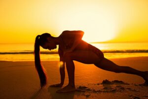 Yoga practitioners meditating at sunset beach in Bali